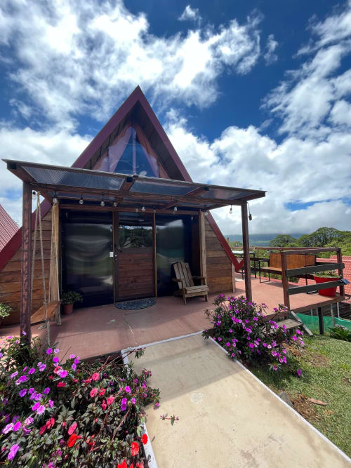 Modern wooden chalet with red peaked roof at Chalets Vistas del Poas in Heredia, Costa Rica, featuring covered terrace and