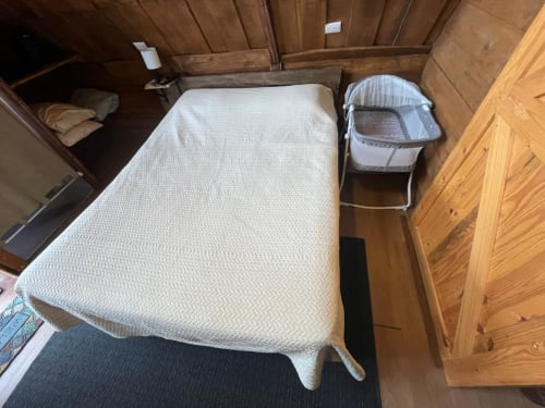 Cozy bedroom at Chalets Vistas del Poas in Heredia with queen bed, white bedding, wooden walls, and portable crib