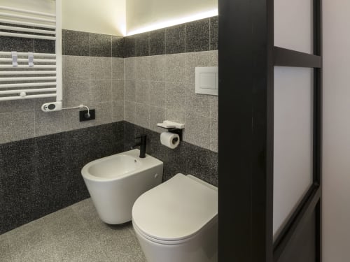 Modern bathroom at YOUnique Boutique Rooms Milan with dual fixtures, dark tile walls, heated towel rail, and contemporary