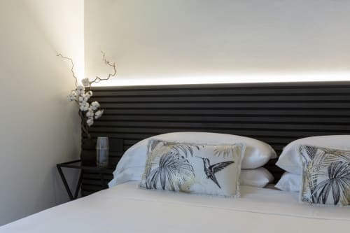 Modern bedroom with dark striped headboard, white bedding, decorative pillows with botanical prints, and minimalist decor at