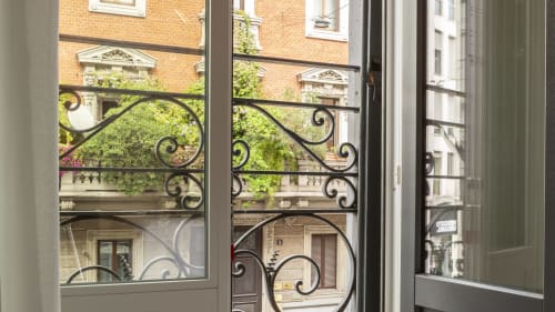 Ornate black wrought iron balcony railing with city view of Milano brick buildings and green foliage from Urban Chic room at