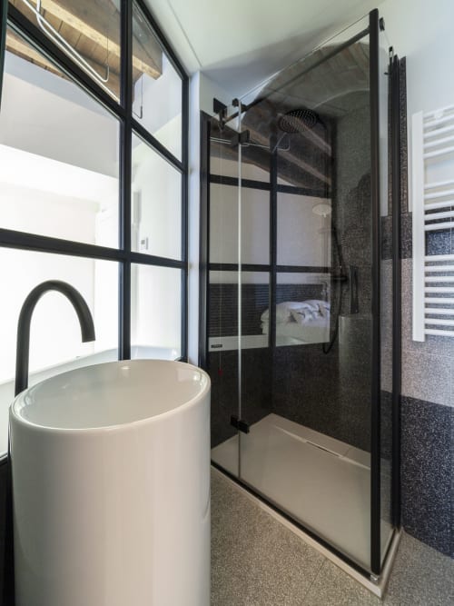 Modern bathroom in Urban Chic room at YOUnique Boutique Rooms Milano, featuring white soaking tub and glass shower enclosure