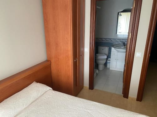 Dormitorio con cama de madera y baño en suite en la Pensión San Vicente, San Vicente de la Sonsierra