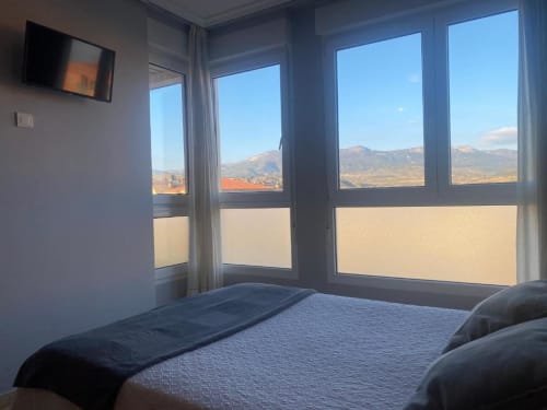 Habitación doble con vistas a la montaña en Pensión San Vicente, con cama, TV y grandes ventanales con vistas a San Vicente de la