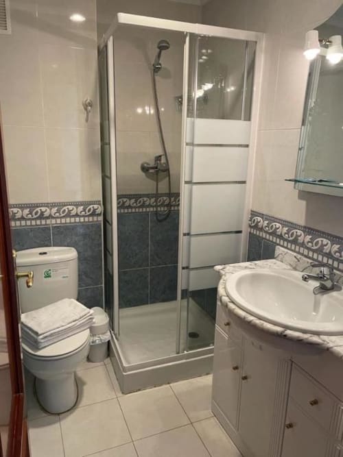 Baño moderno con mampara de ducha, lavamanos redondo e inodoro en la Pensión San Vicente de San Vicente de la Sonsierra