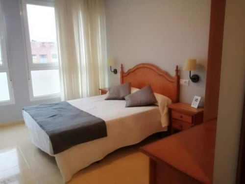 Luminosa habitación doble en Pensión San Vicente con cabecera naranja, vistas a la montaña desde el balcón y comodidades modernas