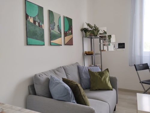 Soggiorno moderno con divano grigio, opere d'arte verde, piante in vaso e vista sul parco a La Casa nel Parco, Campagnano