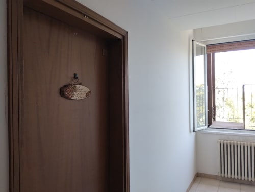 Luminosa hall di appartamento con porta in legno scuro, finestra vista giardino e radiatore a La Casa nel Parco, Campagnano di
