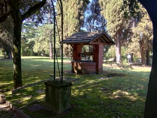 Area giardino ombrosa a La Casa nel Parco, Campagnano di Roma, con pozzo in muratura e alti cipressi