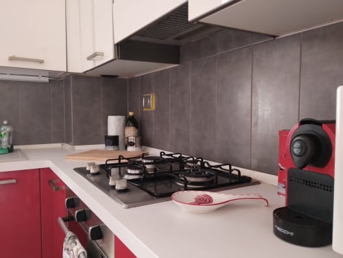 Cucina moderna nell'appartamento La Casetta di Nonna Ro a Campagnano di Roma, con mobili rossi, piano cottura a gas e piastrelle grigie