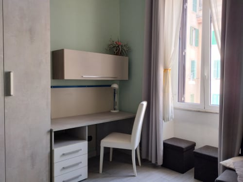 Moderno spazio di lavoro in appartamento con pareti verdi, sedia bianca e vista sulla città da una finestra a Campagnano di Roma