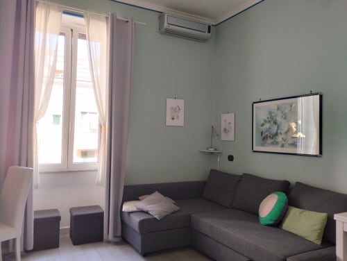 Soggiorno moderno a Campagnano di Roma con divano scuro, opere d'arte a parete, TV a schermo piatto e accesso al balcone