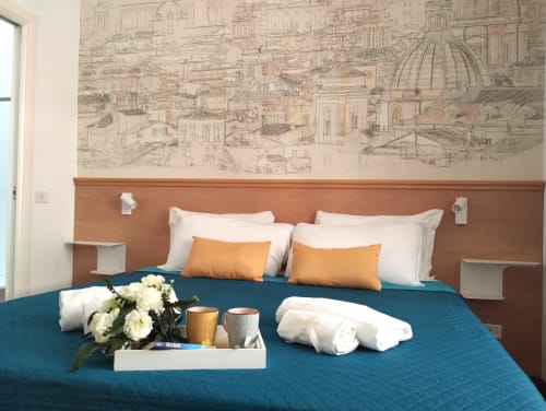 Camera moderna all'hotel Dimora Roma Eterna con letto teal, cuscini arancioni e carta da parati con schizzi della città storica