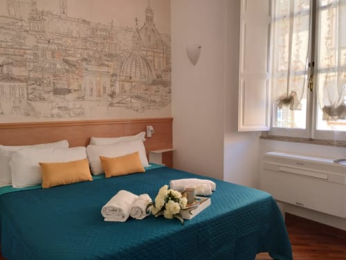 Camera da letto moderna a Roma con biancheria teal, testata in legno, artwork con skyline e servizi accoglienti