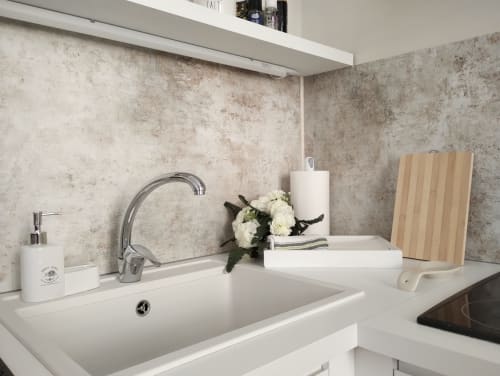 Lavabo moderno con rubinetto cromato, piano di lavoro bianco e rivestimento in piastrelle invecchiate in appartamento a Roma