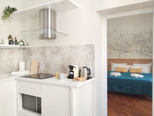 Moderna cucina con cappa in acciaio inossidabile, pensili bianchi e macchina da caffè in appartamento a Roma