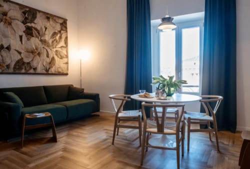 Elegante soggiorno moderno con divano blu, tavolo da pranzo, sedie in legno e vista sulla città di Roma