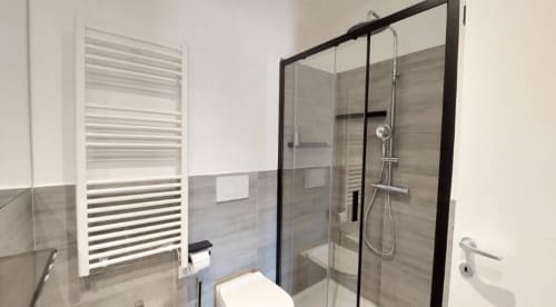 Bagno moderno con box doccia in vetro, scaldasalviette bianco e piastrelle grigie a Dimora S. Bartolomeo
