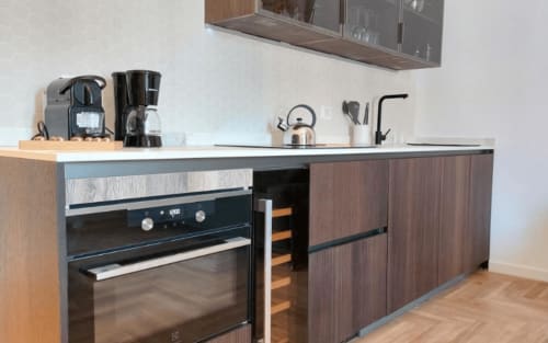 Cucina moderna nell'appartamento di Campagnano di Roma con mobili in legno scuro, forno integrato, macchina da caffè e piano in bianco