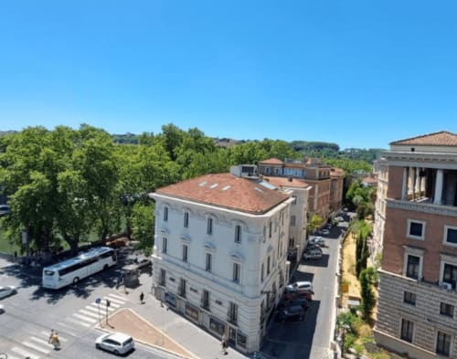 Vista aerea dell'edificio storico bianco a Campagnano di Roma con strade, auto parcheggiate e alberi verdi sotto cielo sereno