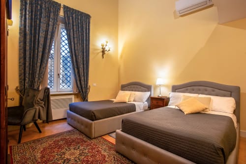 Camera matrimoniale in Residenza Sinibaldi, Campagnano di Roma con letti imbottiti, pareti gialle e finestra con vista sulla città