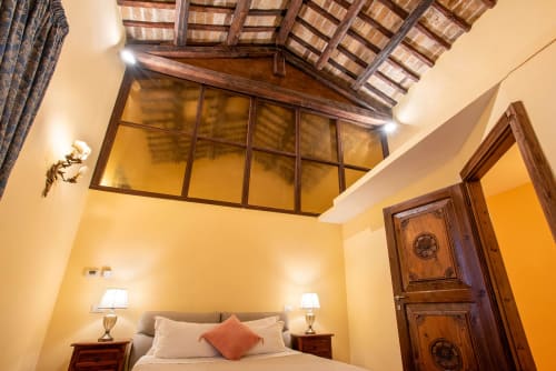 Camera elegante alla Residenza Sinibaldi di Campagnano di Roma, con travi in legno, illuminazione calda e arredi classici