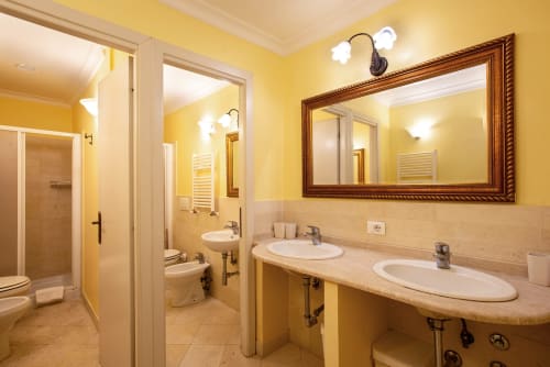 Bagno spazioso nella Residenza Sinibaldi, Campagnano di Roma con doppio lavabo, pareti gialle e mobile in legno