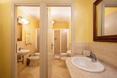 Bagno moderno della Residenza Sinibaldi a Roma con doppio lavabo, toilette, doccia e pareti gialle