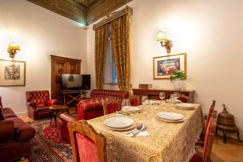 Elegante sala da pranzo della Residenza Sinibaldi a Campagnano di Roma, con tavolo apparecchiato, sedie in pelle rossa e arredamento classico