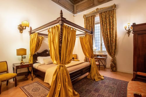 Elegante letto a quattro colonne con drappeggi dorati nella Residenza Sinibaldi di Campagnano di Roma, con arredi d'epoca e vista città