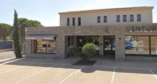 Guest by ALMA ROSSA hotel entrance in Lecci with stone facade, landscaping, and parking area