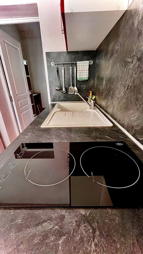Modern kitchen at Le Maquis Plage hotel with induction cooktop, sink, and dark stone countertops in Poggio-Mezzana