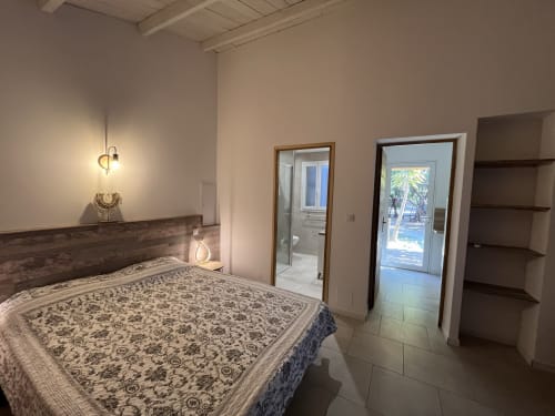 Spacious bedroom at Le Maquis Plage with queen bed, ensuite bathroom, and patio access in Poggio-Mezzana