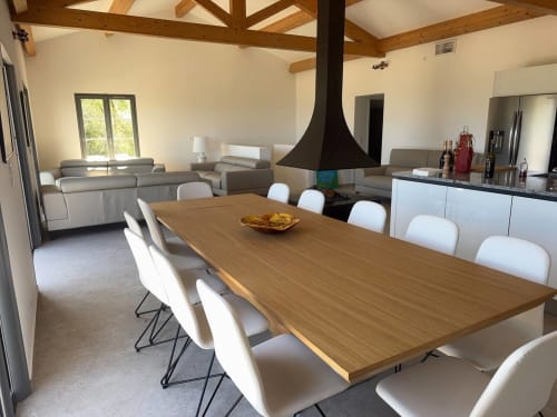 Salle à manger moderne de la villa avec table en bois, chaises blanches et suspension noire dominant le salon à La Conciergerie
