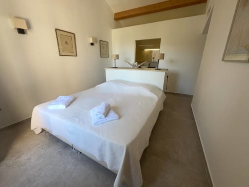Chambre moderne à la Villa Marine à Centuri avec lit blanc, poutres en bois et décor minimaliste corse