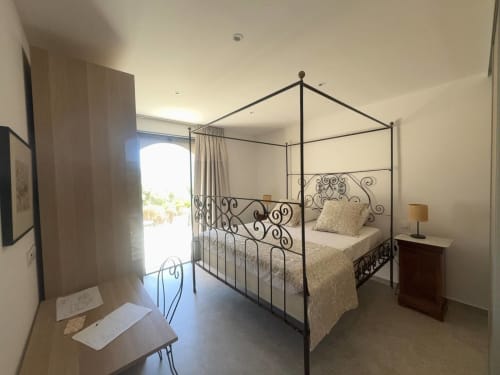Chambre élégante avec lit à baldaquin en fer forgé orné et vue sur mer à Villa Marine, La Conciergerie du Cap Corse
