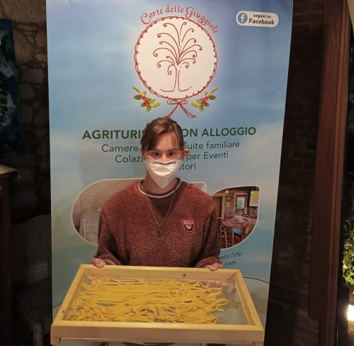 Membro dello staff della Corte delle Giuggiole B&B a Cologna Veneta che mostra pasta fresca durante un evento agriturismo