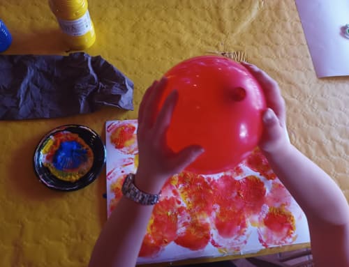Mano di bambino che tiene un palloncino rosso sopra un'opera d'arte colorata alla Corte delle Giuggiole B&B a Cologna Veneta