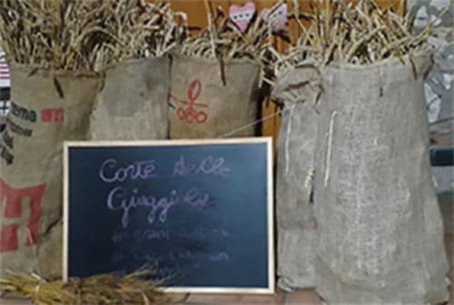Sacchetti di carta con paglia e cartello in ardesia con scritto 'Corte delle Giuggiole' presso la guest house di Cologna Veneta