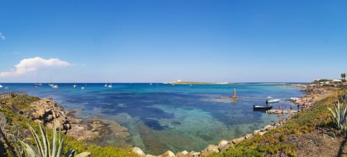 Baia turchese di Fontane Bianche con barche a vela, spiaggia sabbiosa e vista di ville costiere mediterranee