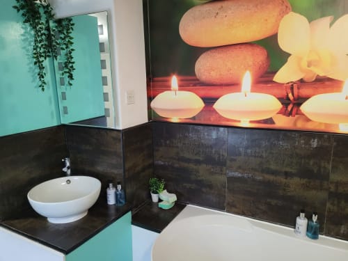 Modern bathroom at Jane's B&B Guisborough villa with white vessel sink, black tile backsplash, spa-themed wall art, and