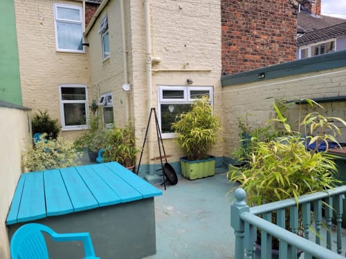 Compact patio garden at Jane's B&B villa in Guisborough with blue furniture, potted plants, and stone paving