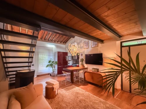 Loft moderno Cognaia ad Arezzo con soffitto in legno caldo, arredi arancioni, cucina, scala e piante