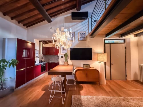 Cognaia Loft ad Arezzo - appartamento moderno con cucina rossa, travi in legno, lampadario a sospensione e zona living accogliente