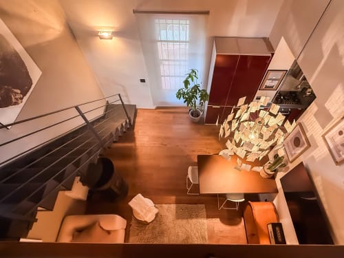 Vista dall'alto del loft Cognaia ad Arezzo: ampio spazio con pavimenti in legno, scala per soppalco e arredamento completo