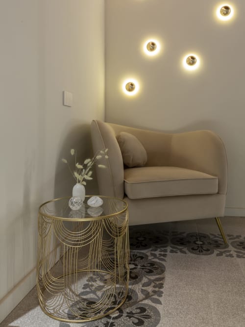 Romantic room corner at YOUnique Boutique Rooms Milano with beige armchair, brass side table, and warm ambient wall lights