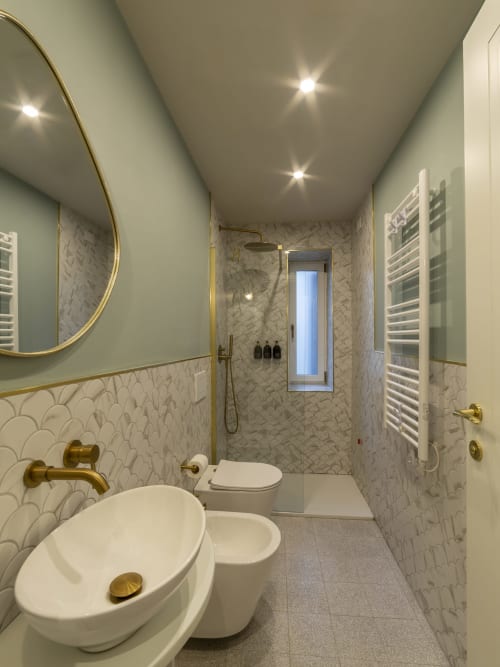 Modern luxury bathroom at YOUnique Boutique Rooms Milano with marble tile, brass fixtures, round sink, and rainfall shower