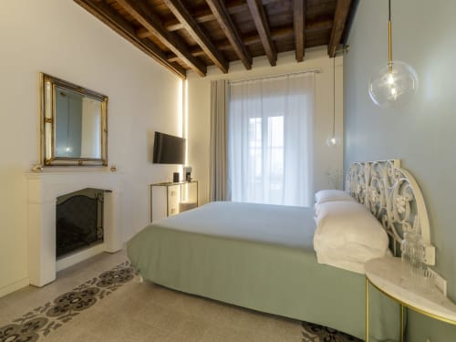 Elegant romantic bedroom at YOUnique Boutique Rooms Milano with fireplace, ornate headboard, and city view balcony