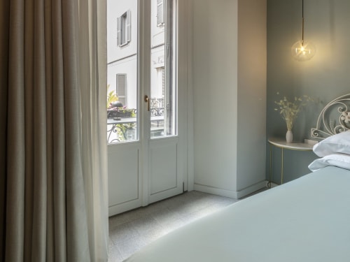 Romantic Milan hotel room with city view balcony, modern furnishings, and pendant lighting at YOUnique Boutique Rooms