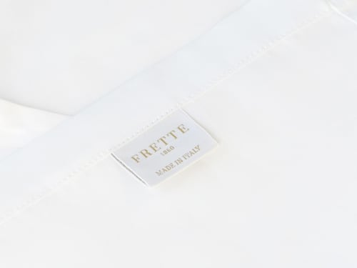 Etichetta di lusso FRETTE 1860 su biancheria bianca presso YOUnique Boutique Rooms Milano